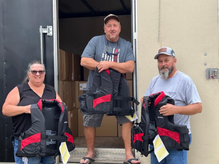 KRVSA leadership holding some of the red and black life vests donated to the FWC.